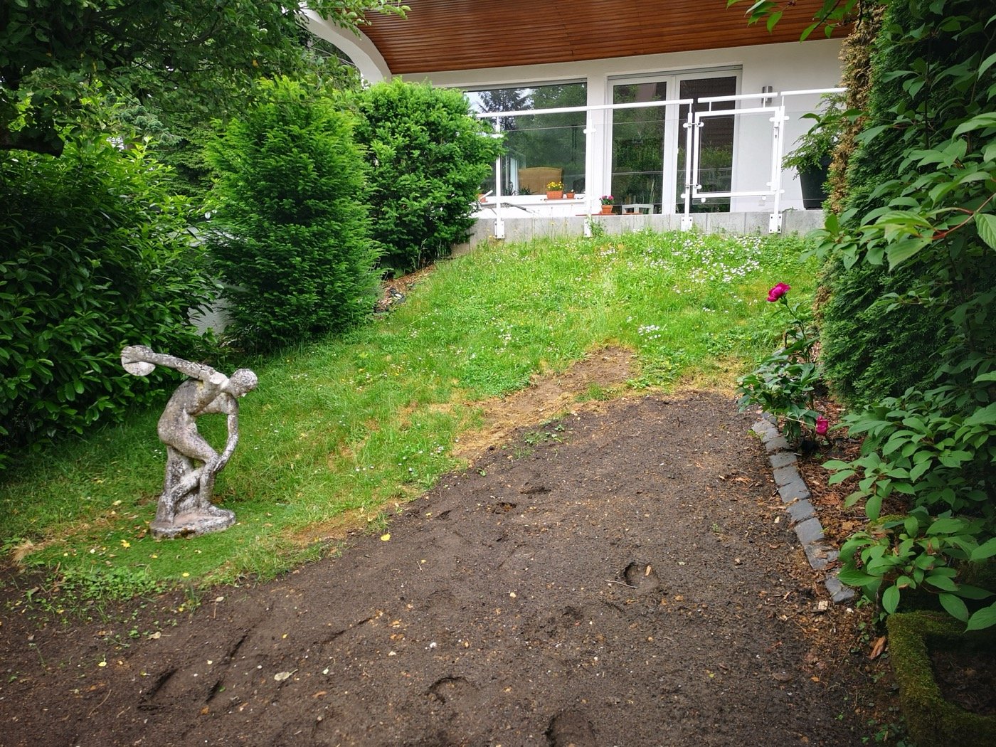 Rasenfläche mit Steinfigur, verwildert
